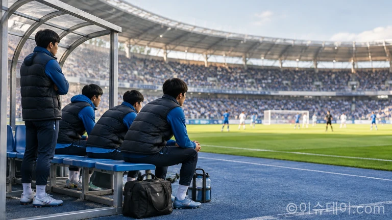 축구 경기장 벤치 좌석에 앉아 진지한 표정으로 경기를 지켜보는 선수들의 모습