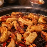 숯불 화로 위에서 구워지고 있는 명륜진사갈비 숯불통막창 신메뉴