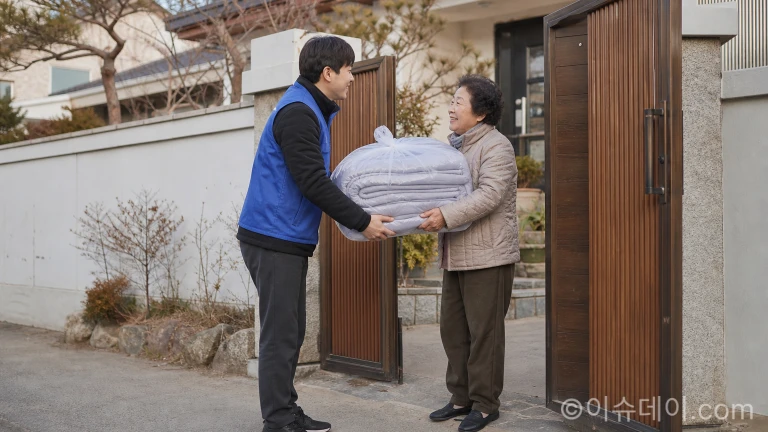 가정집 대문 앞에서 봉사자가 주민에게 방한 이불을 건네는 모습